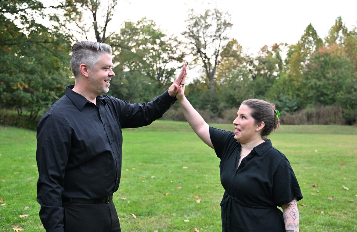 Two ensemble members share a high five outdoors